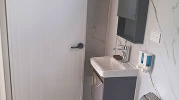 A bathroom with a white door, a sink, a mirror, and a toilet.