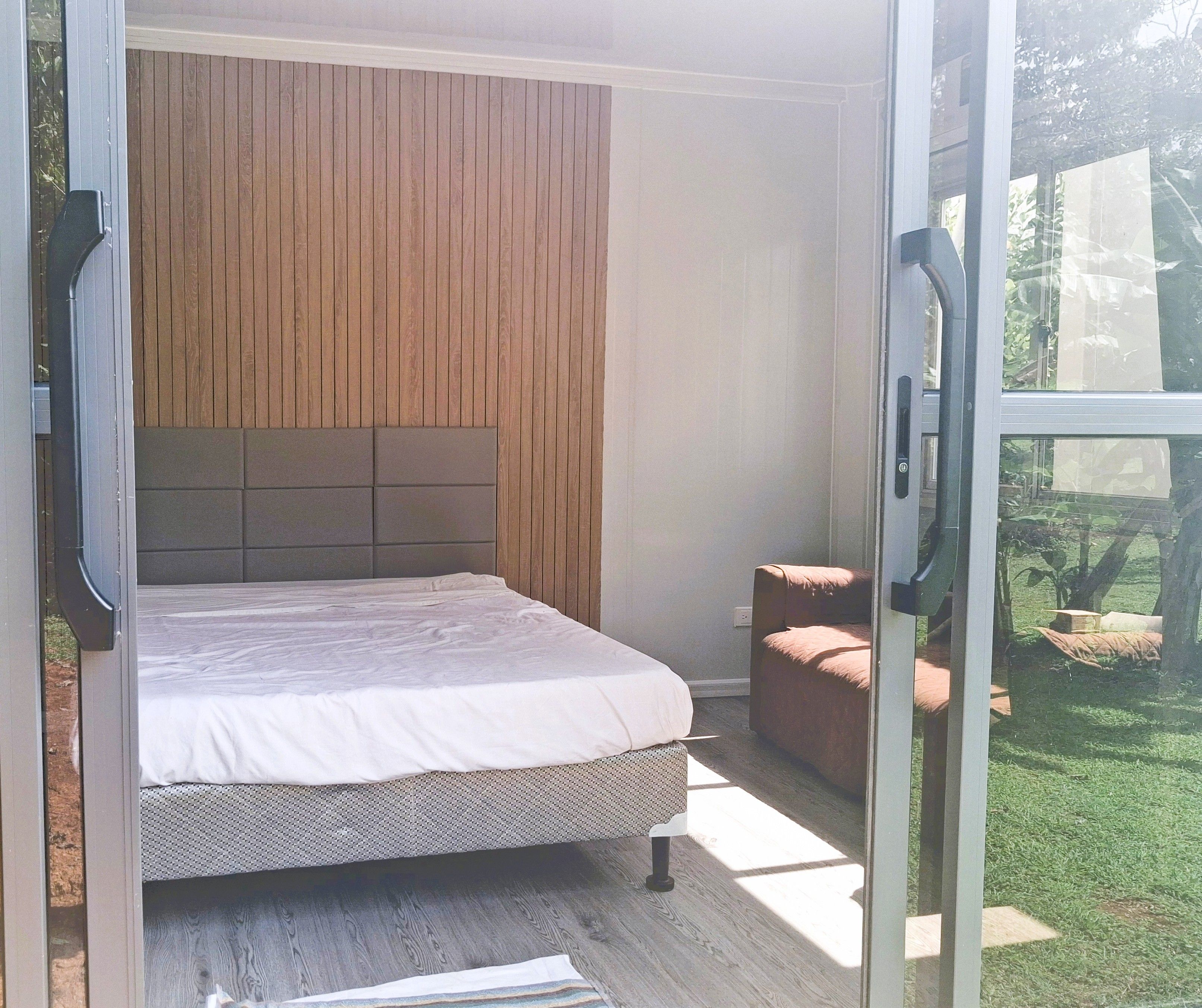 A bedroom with a bed, a headboard, and a view of the outdoors.