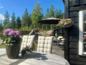 An outdoor seating area with cushioned chairs, a table, and a hanging flower basket. - Family cabin near Trysilfjellet (Nybergsund)