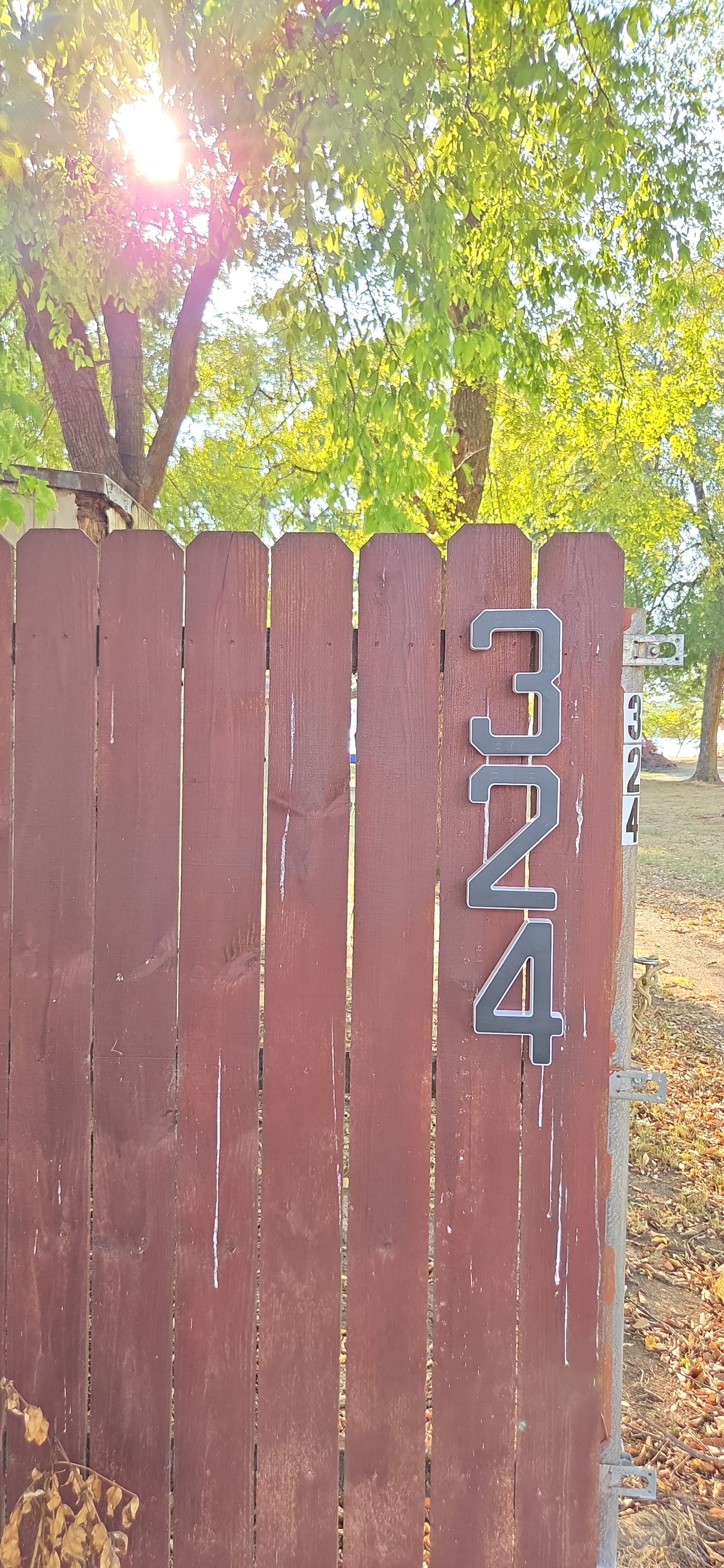 A wooden fence with a metal sign displaying the number '3'.