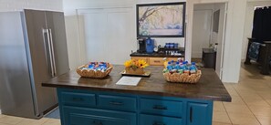 Una encimera de cocina con tres cestas tejidas que contienen aperitivos y un florero con flores amarillas.