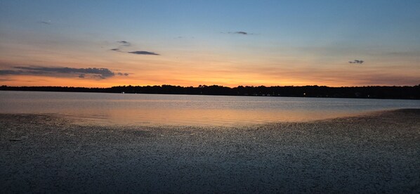 A beach with a calm water surface reflecting the sky.