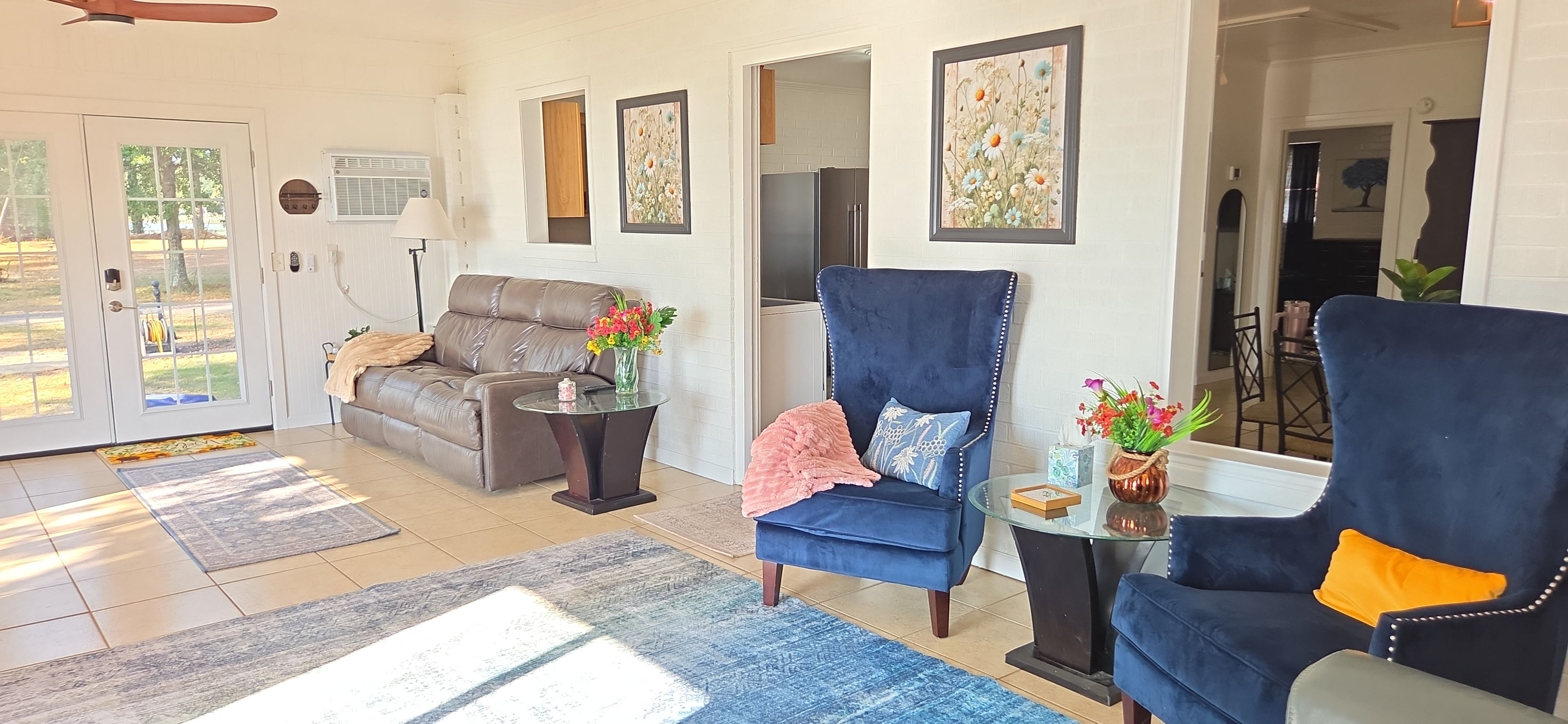 A living room with a sofa, a blue armchair, a glass coffee table, and a rug.