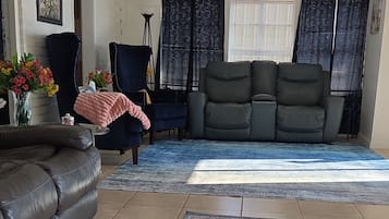 A living room with a sofa, a chair, a rug, and a welcome mat.