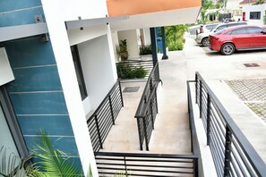 A multi-level building with a staircase, railings, and a parking area with cars. - Elegant, ultra modern 1-bedroom studio apartment with AC in tranquil Ocho Rios (Ocho Rios)