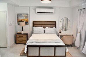 Ein modernes Schlafzimmer mit Bett, Nachttischen, einer Lampe, einer Klimaanlage, einem Gemälde und einem Spiegel.