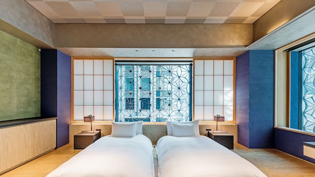 A modern hotel room with a large bed, two bedside tables, and a large window with a geometric pattern. - Playwright Test Hotel 1789607849240 (Seattle)