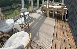 A covered outdoor patio with a table and chairs, a glass-top table, and a woven rug. - Gorgeous home in Juelsminde with WiFi (Juelsminde)