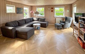 A living room with a sectional sofa, a small ottoman, a chair, a TV, and a wooden bookshelf. - Gorgeous home in Juelsminde with WiFi (Juelsminde)