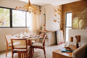 A dining area with a round table set for four, surrounded by wicker chairs. - Casa Deslumbrante a 3min a pe do mar (Sao Miguel dos Milagres)
