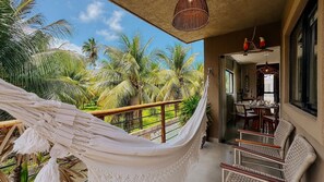 Un'amaca su un balcone con vista su un giardino tropicale e palme.