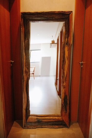 A hallway with a wooden door frame leading to a room with a white floor and a chair. - Casa Deslumbrante a 3min a pe do mar (Sao Miguel dos Milagres)