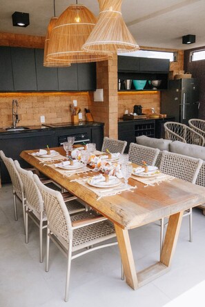 Una cocina moderna con una mesa de comedor alargada para seis personas, rodeada de sillas de mimbre.
