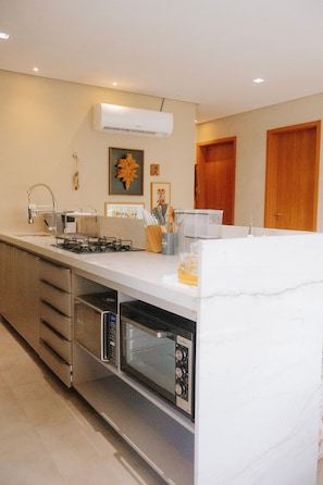 A modern kitchen with a central island, built-in appliances, and a clean design. - Casa Deslumbrante a 3min a pe do mar (Sao Miguel dos Milagres)