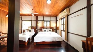 Una habitación tradicional japonesa con dos camas individuales, suelo de madera y ventilador de techo.