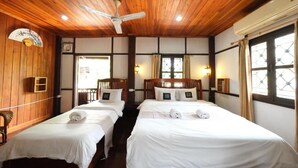 Habitación de hotel con dos camas, techo de madera, ventilador de techo, aire acondicionado de pared y ventanas con cortinas.