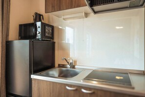 A compact kitchenette with a stainless steel refrigerator, a microwave, and a sink. - Apartment Hotel 11 Tsutenkaku 3 (Osaka-shi)