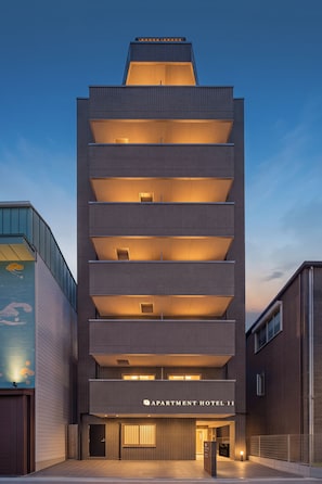 A multi-story building with a modern design, featuring a prominent entrance with a sign reading 'APARTMENT HOTEL II'. - Apartment Hotel 11 Tsutenkaku 3 (Osaka-shi)