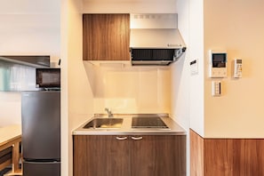Eine kompakte Küche mit Einbauherd, Kühlschrank und Mikrowelle.