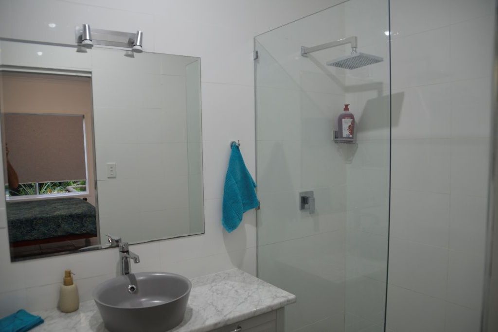 A bathroom with a sink, mirror, and glass shower enclosure.