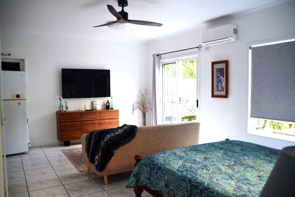 Ein Schlafzimmer mit einem Bett, einem Schminktisch, einem Fernseher und einem Fenster.