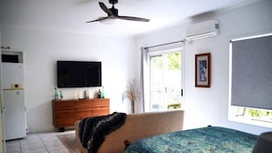 Ein Schlafzimmer mit einem Bett, einem Schminktisch, einem Fernseher und einem Fenster.