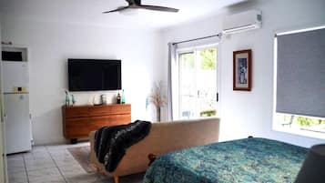 Ein Schlafzimmer mit einem Bett, einem Schminktisch, einem Fernseher und einem Fenster.