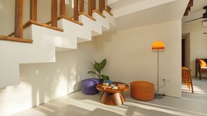 Un interior modern amb una escala, una taula rodona amb objectes, una làmpada de peu i una planta en test.
