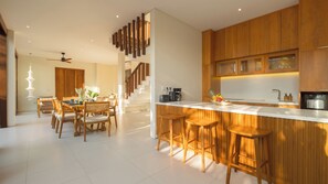 A modern kitchen with wooden cabinetry, a white countertop, and a built-in coffee maker. - Villa Omah Bumbak (Badung)