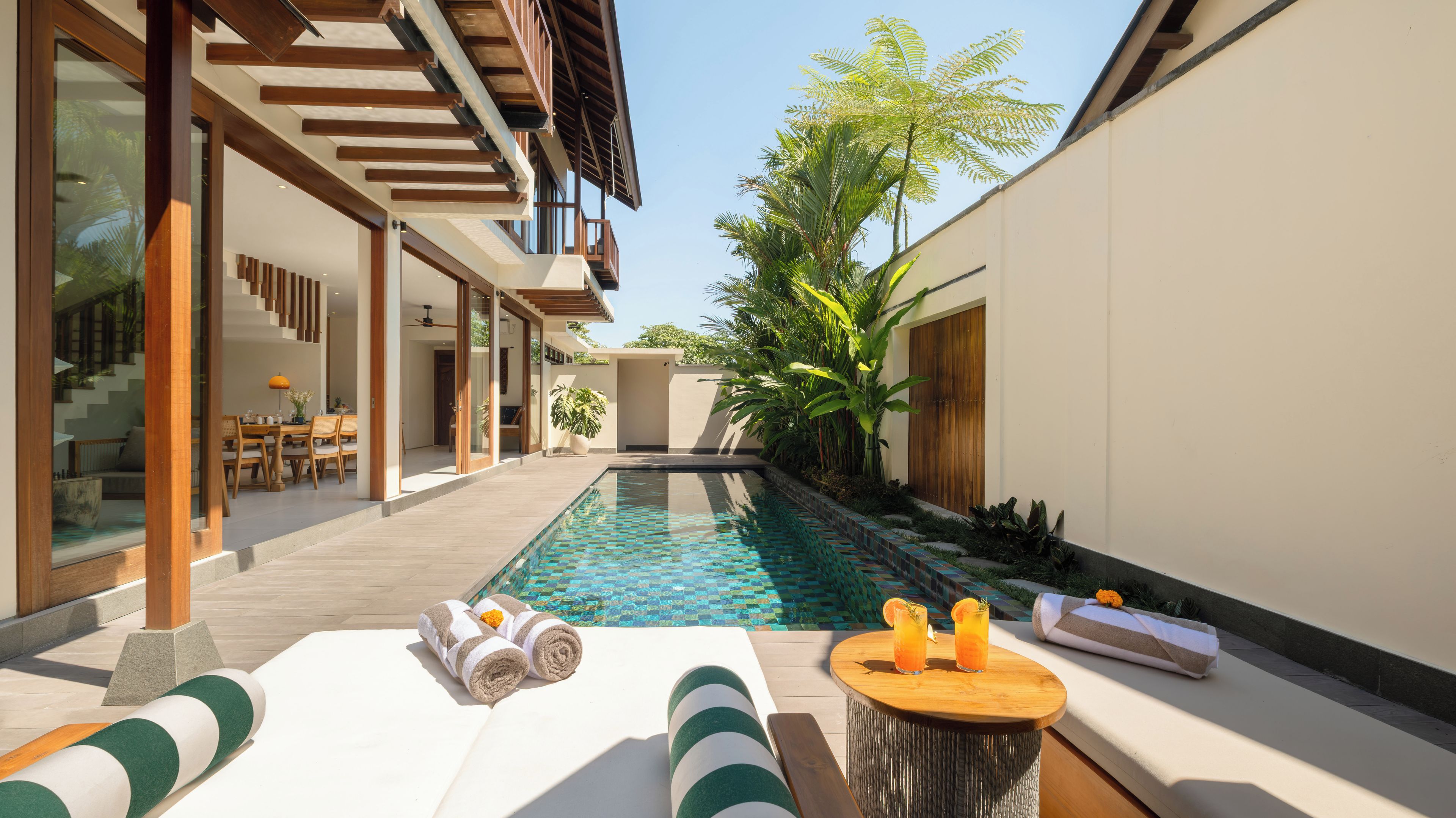 A poolside area with a lounge chair, towels, and a small table with drinks.