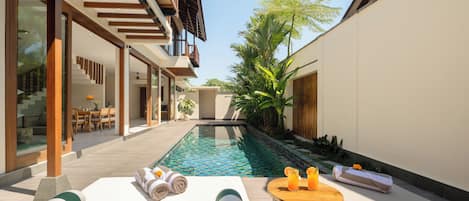 A poolside area with a lounge chair, towels, and a small table with drinks.