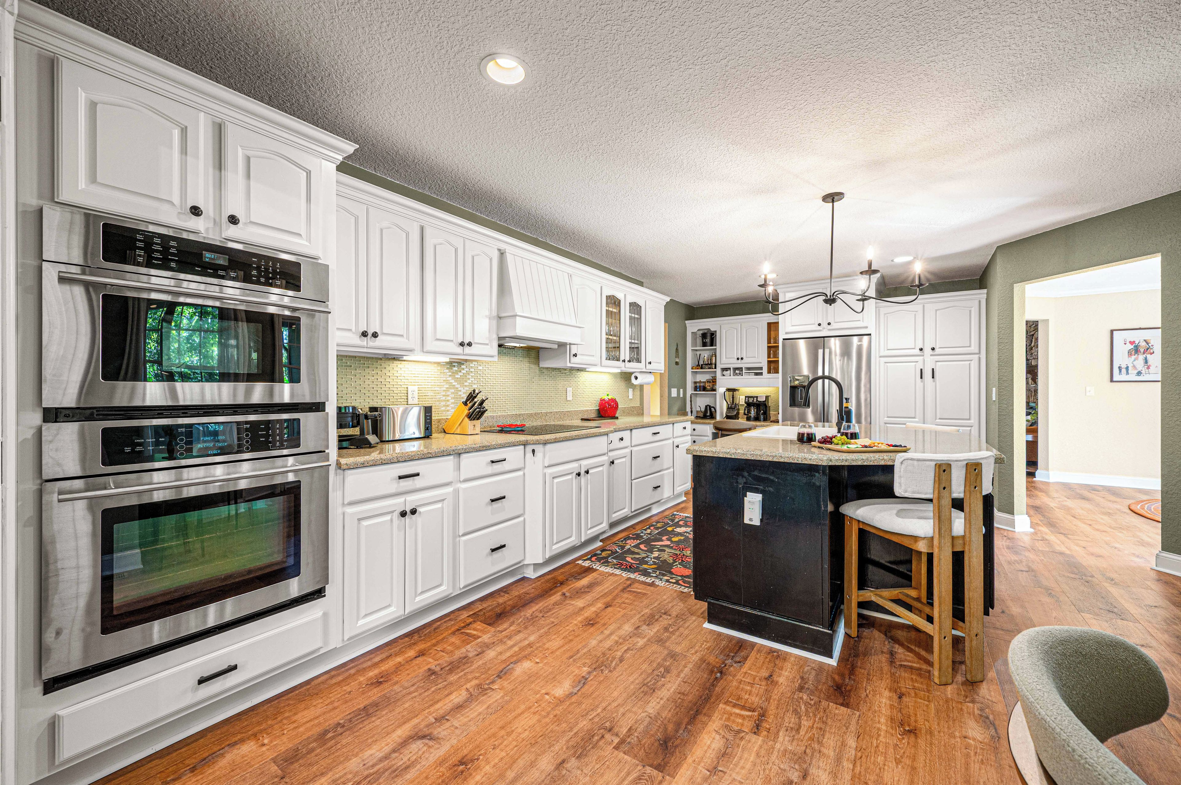 A modern kitchen with white cabinetry, stainless steel appliances, and a central island with bar stools.