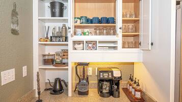 Une cuisine équipée d’un espace dédié à la préparation du café, comprenant une machine à café, un moulin et un espace de rangement pour les grains de café.