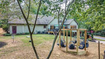 A residential property with a house, a swing set, and a fenced yard.