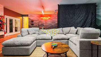 A modern living room with a sectional sofa, a coffee table, and a wall with a neon sign.