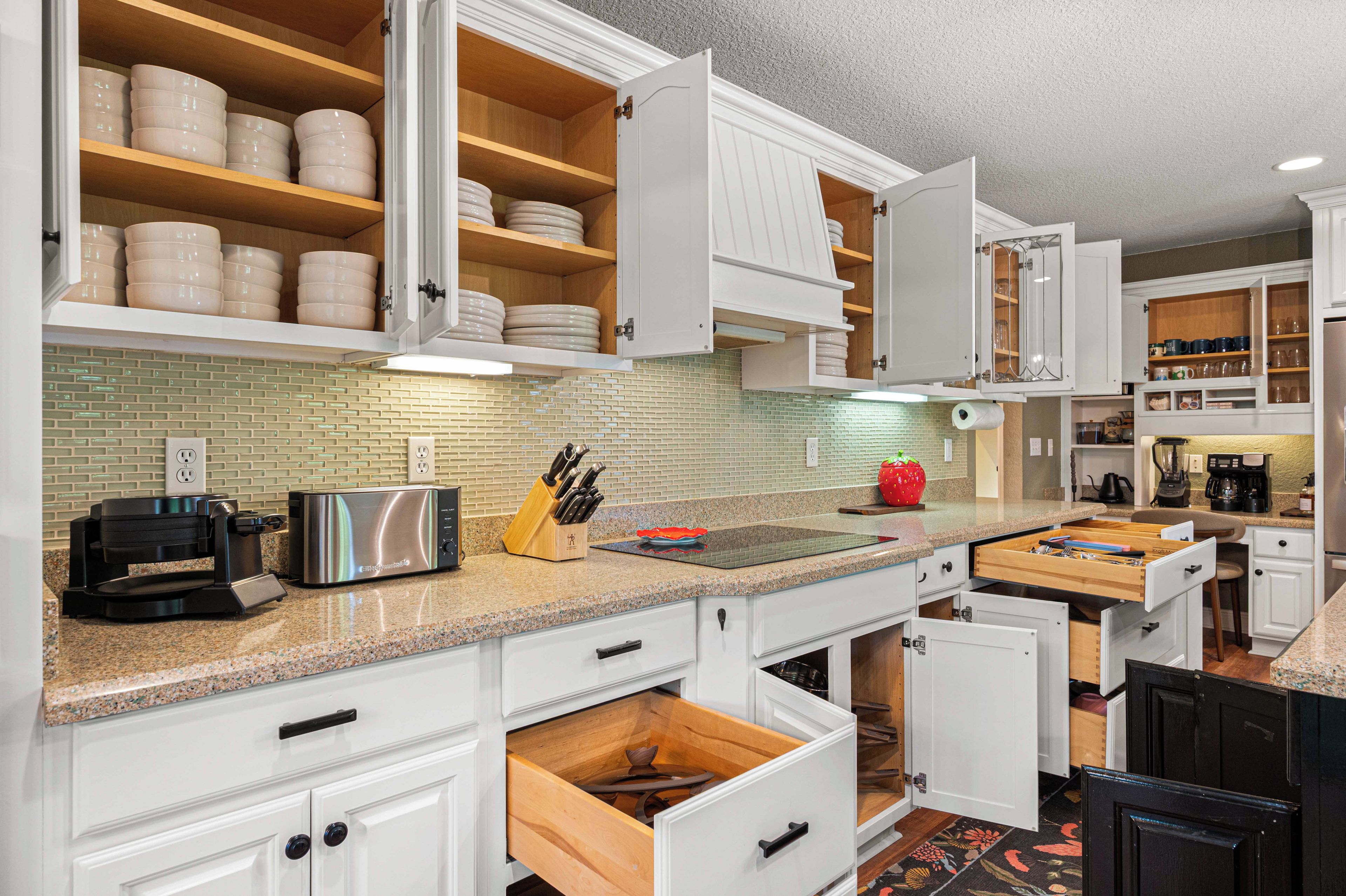 A kitchen with white cabinetry, a toaster, a knife block, and a coffee maker.
