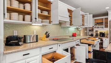 A kitchen with white cabinetry, a toaster, a knife block, and a coffee maker.