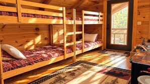 Een chalet met stapelbedden, een houten vloer, een vloerkleed met dierenprint en een deur met uitzicht op de omgeving.