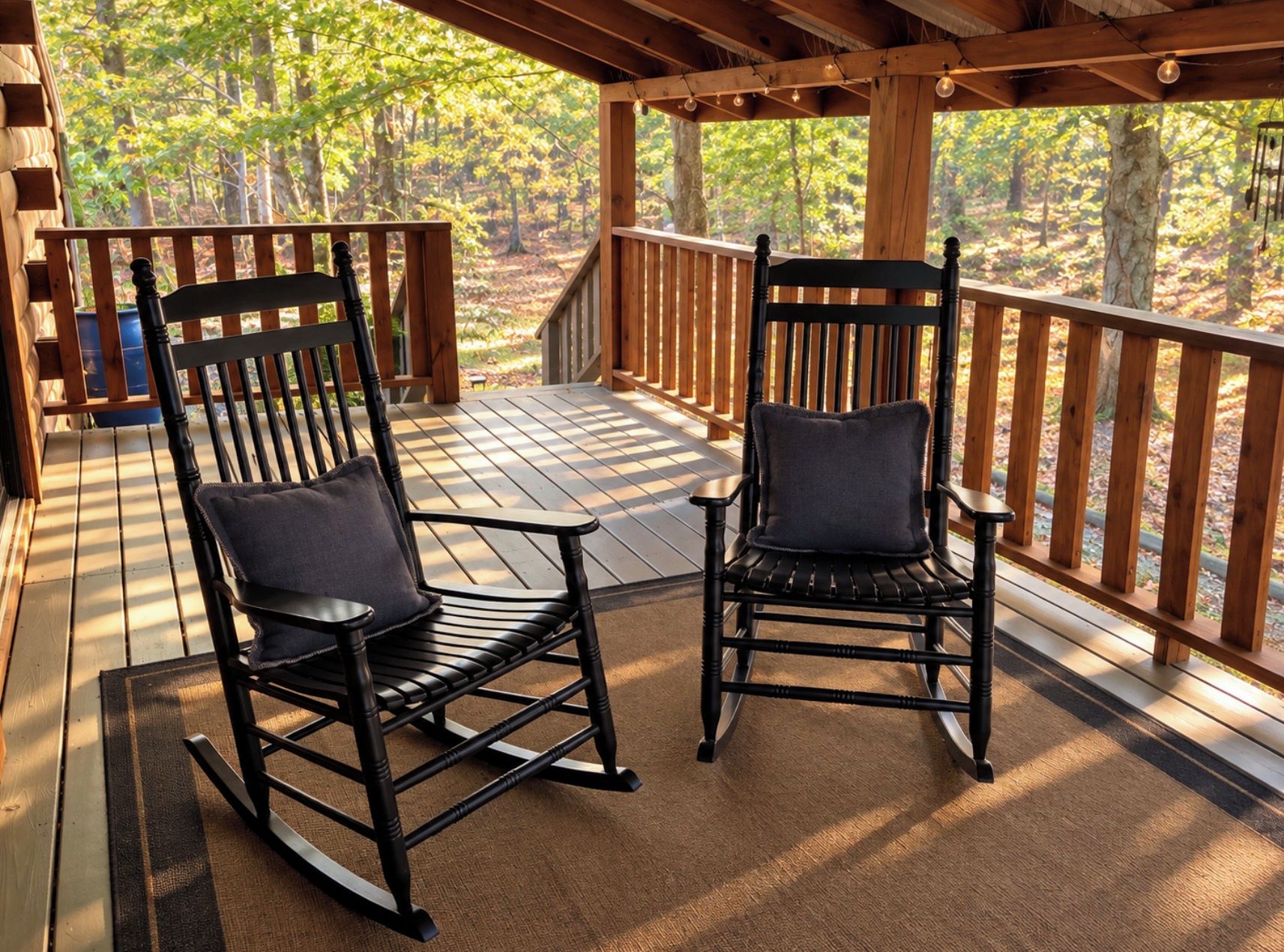 A wooden deck with two rocking chairs and a table.