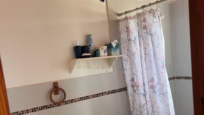 A bathroom with a toilet, sink, shower curtain, and a shelf with toiletries. - perfect for family. Angler and nature guides (Owens Town)