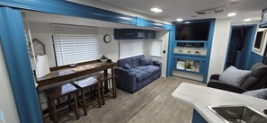 A compact living space with a kitchenette, a dining area, and a seating area with a sofa and chairs. - Country Camping w/farm amimals (Brooksville)