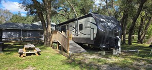 A mobile home with a ramp leading to a deck, a picnic table, and a sign that reads 'FARM'. - Country Camping w/farm amimals (Brooksville)
