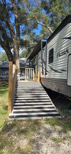 A covered outdoor area with a wooden ramp leading to a vehicle. - Country Camping w/farm amimals (Brooksville)
