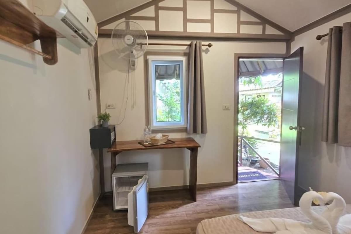 Ein Zimmer mit einem Bett, einem Schreibtisch, einem Fenster und einer Tür zu einem Außenbereich.