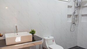 Ein modernes Badezimmer mit Toilette, Waschbecken mit Spiegel und Duschbereich.