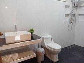 Ein modernes Badezimmer mit Toilette, Waschbecken mit Spiegel und Duschbereich.