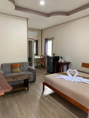 Ein Hotelzimmer mit einem Bett, einer Couch, einem kleinen Tisch und einem Schreibtisch.
