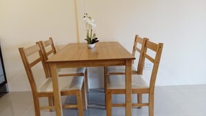 Ein Holztisch mit vier Stühlen, einer kleinen Topfpflanze und einem Fliesenboden.