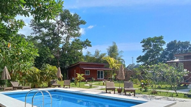 Una piscina con una escalera metálica, rodeada por un solárium con baldosas y muebles de exterior.