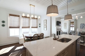 Una cucina moderna con una grande isola, illuminazione a sospensione e un'area pranzo con tavolo e sedie.